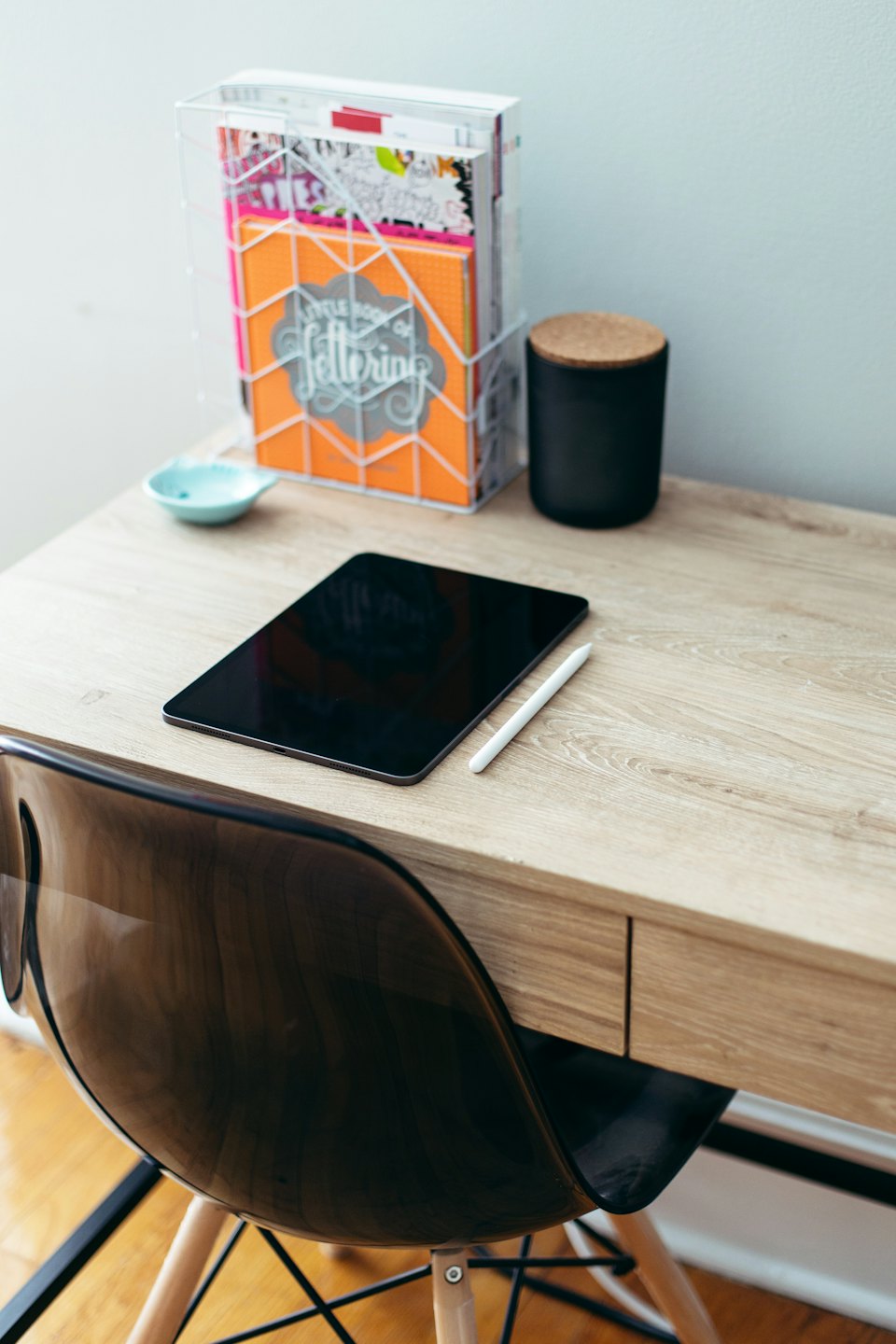 Tablet e stilo su una scrivania di legno chiaro con quaderni.